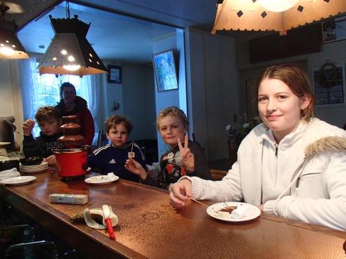 a woman sitting at a table with a group of children at Rosenheim Hakuba in Hakuba