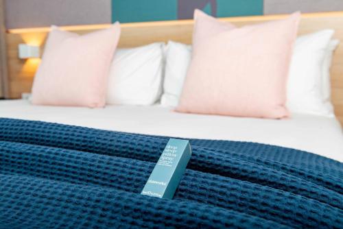 a bed with a blue blanket with a book on it at Crowne Plaza Adelaide by IHG in Adelaide