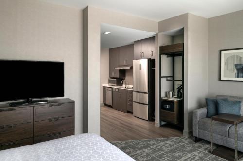 a living room with a television and a kitchen at Staybridge Suites - Boston Logan Airport - Revere by IHG in Revere