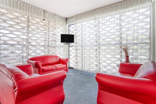 a living room with red chairs and a tv at Hotel Suites Puebla in Puebla