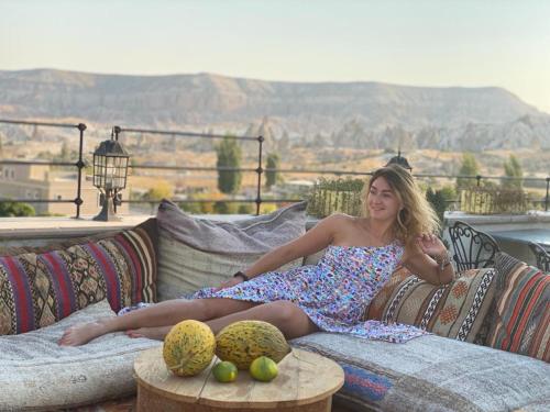 a woman in a dress sitting on a couch at Caravanserai Inn Hotel in Goreme