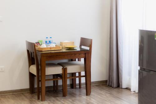 a small table with two chairs and a table and a refrigerator at REIWA INN APARTMENT in Hanoi