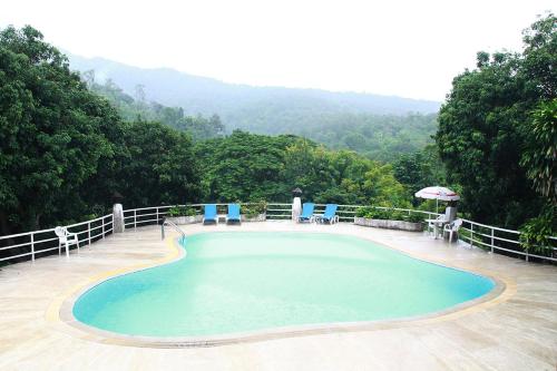a large swimming pool with chairs and an umbrella at Mae Sa Valley Garden Resort in Ban Mae Mae