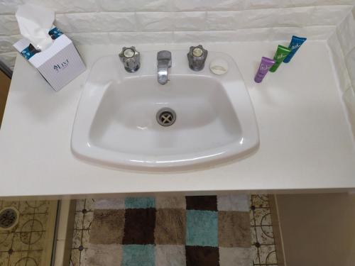 a white sink with toothbrushes and toothpaste on a counter at Toukley Motel in Toukley