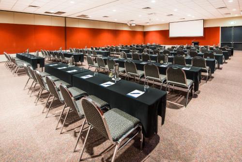 a conference room with tables and chairs and a screen at Crowne Plaza Alice Springs Lasseters by IHG in Alice Springs