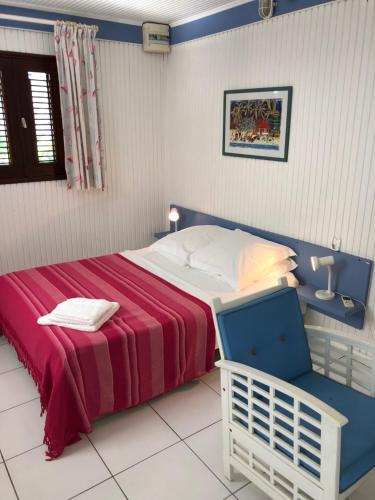 1 dormitorio con 1 cama con manta roja y silla en Coco-Mango Apt C, en Deshaies