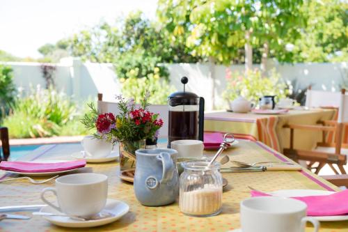 een tafel met borden en kopjes en een koffiezetapparaat bij Cornerway House in Plettenbergbaai