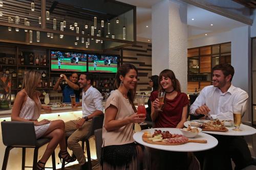 a group of people sitting in a bar with plates of food at Real Intercontinental Metrocentro Managua by IHG in Managua
