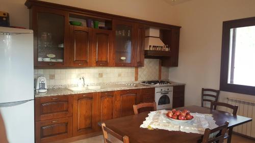 una cocina con armarios de madera y una mesa con un bol de fruta en Villa nel verde, en Iglesias