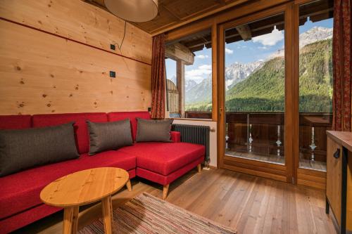 a living room with a red couch and a table at Berghotel - Sexten in Sesto