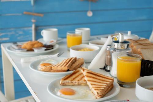 a breakfast table with eggs and bread and orange juice at Sagma Beach Rooms in Perissa