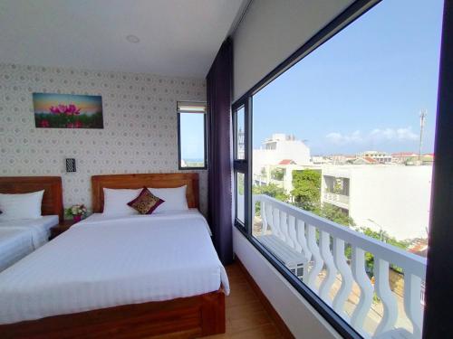 1 dormitorio con 2 camas y ventana grande en Heritage Hotel, en Tuy Hoa