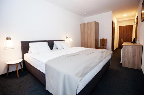 a hotel room with a large bed with white sheets at Penzion Dolíček in Cheb