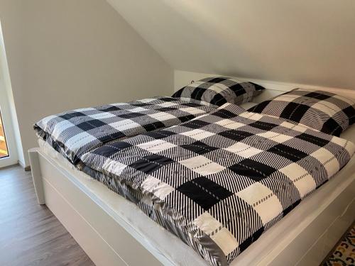 Una cama con una manta a cuadros en blanco y negro. en WG Ragöser Wasserrad en Sandkrug