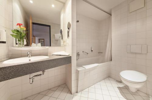 a white bathroom with a toilet and a sink at Novum Hotel Seegraben Cottbus in Cottbus