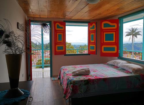 a bedroom with a bed in a room with windows at Casa Pachamama in Salento
