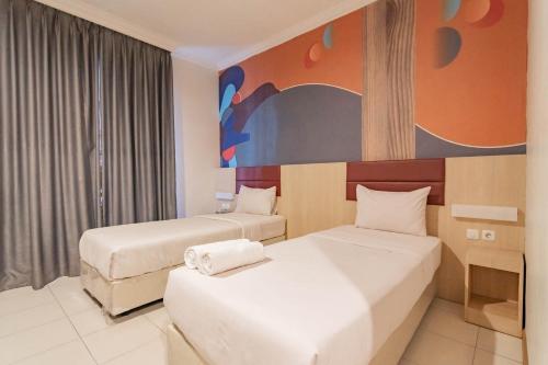 una habitación de hotel con 2 camas y un cuadro en la pared en RedDoorz At Hotel Arimbi Dewi Sartika Baru, en Bandung