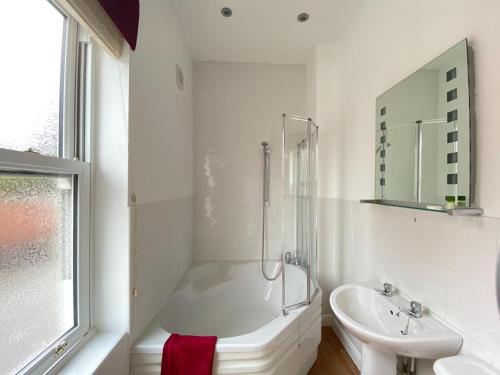 a white bathroom with a sink and a tub and a toilet at The Victoria in Newcastle under Lyme