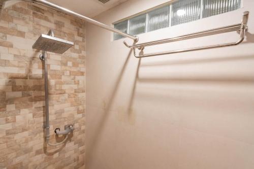 a shower in a bathroom with a stone wall at RedDoorz At Hotel Arimbi Dewi Sartika Baru in Bandung