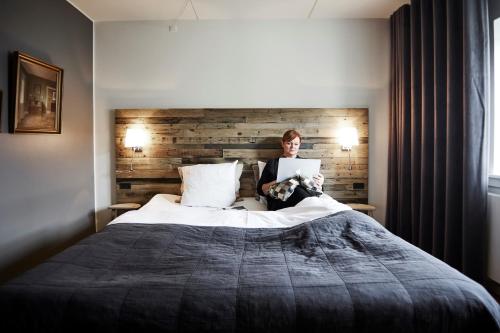a woman sitting on a bed using a laptop at Haraldskær Sinatur Hotel & Konference in Vejle