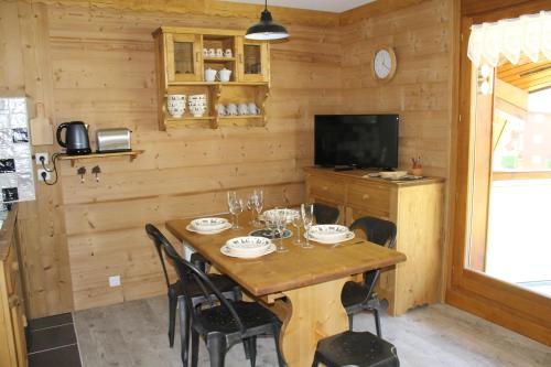 ein Esszimmer mit einem Tisch mit Stühlen und einem TV in der Unterkunft L'Enclave in Les Contamines-Montjoie