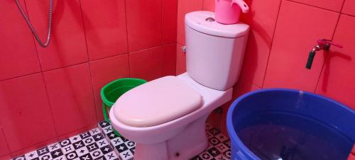 a red bathroom with a toilet and a bucket at Penginapan Pendopo Kasih in Pugeran