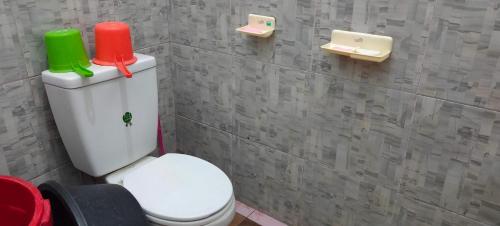 a bathroom with a toilet with a red and green candle on it at Penginapan Pendopo Kasih in Pugeran