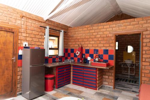 a kitchen with a refrigerator and a brick wall at Otavi Vineyards Self-Catering & Camping in Otavi