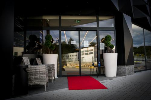 a red rug in front of a building with a window at Hotel Bank in Kiseljak