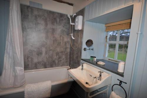 a bathroom with a tub and a sink and a bath tub at Blairbeg Cottage in Blairgowrie