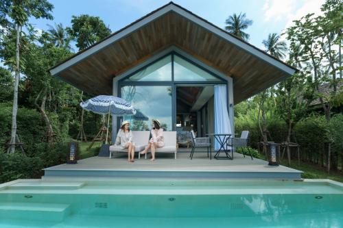 two women sitting on the porch of a house with a pool at Island Escape Burasari in Phuket Town
