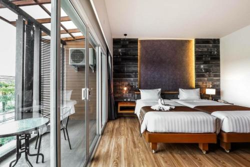 1 dormitorio con 2 camas y pared de cristal en The Glory Gold en Khao Lak