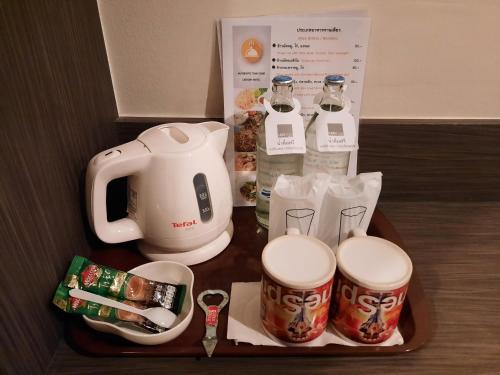 a tray with a coffee maker and cups on a table at Leosor Hotel in Nakhon Ratchasima