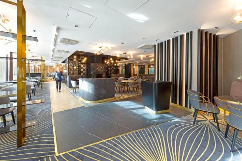 a lobby of a restaurant with tables and chairs at Crowne Plaza Helsinki - Hesperia by IHG in Helsinki