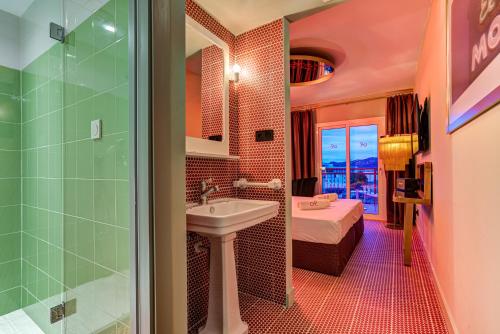 a bathroom with a sink and a shower and a bed at Romeos Ibiza - Adults Only in San Antonio Bay