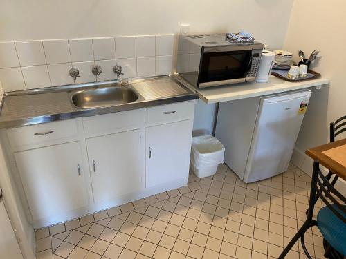 a kitchen with a sink, microwave, and dishwasher at Tollgate Motel in Adelaide