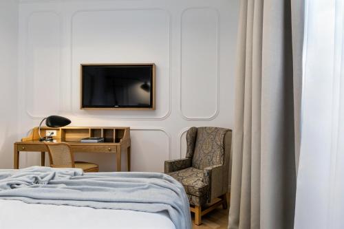 a hotel room with a bed and a chair and a television at Heritage Hotel FERMAI MGallery Split in Split