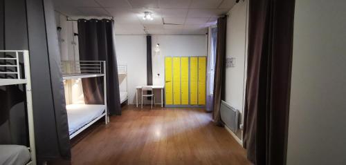 a room with two bunk beds and a yellow door at Le Coffice Auberge de Jeunesse in Paris
