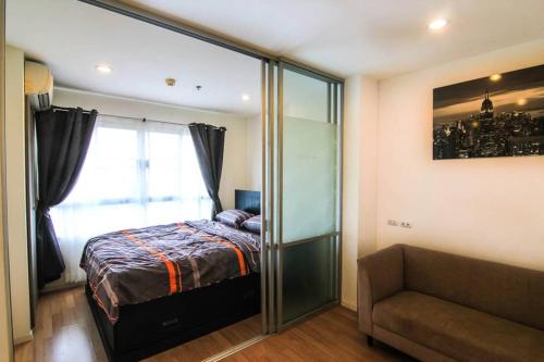 a bedroom with a bed and a window and a couch at Nice Condo near Ramkhamhaeng 60, Lam Sali MRT in Bangkok