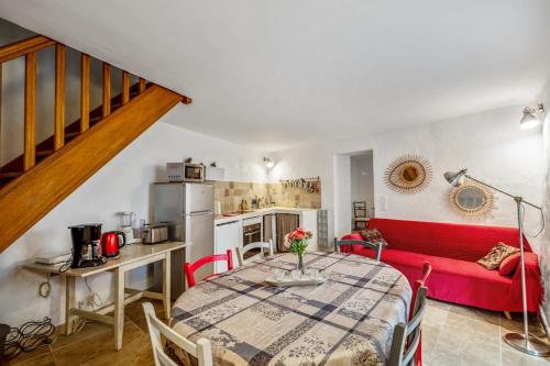 un salon avec une table et un canapé rouge dans l'établissement Maison de village, à Bonnieux