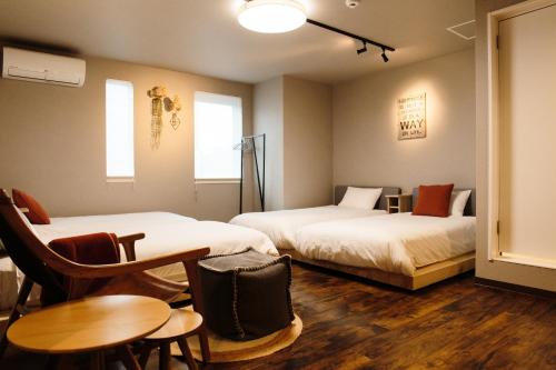 旭川市にあるLampstand STAY Asahikawaのベッド2台、テーブルと椅子が備わるホテルルームです。