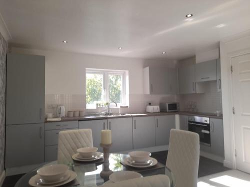 a kitchen with a glass table and chairs and a kitchen with white cabinets at Penthouse Apartment FREE wi-fi & Parking Occasional Bed Available in Solihull