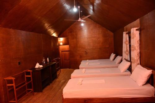 een kamer met vier bedden en een tafel erin bij Cinnamon Village Sinharaja in Deniyaya