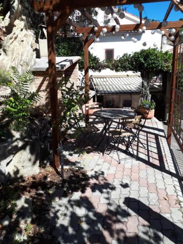 a patio with a table and a wooden pergola at Apricot House in Roccascalegna