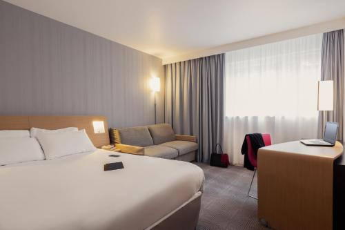 a hotel room with a bed and a chair at Novotel Roissy Saint Witz in Saint-Witz