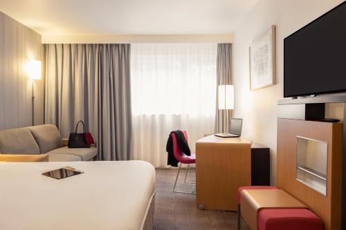 a hotel room with a bed and a couch at Novotel Roissy Saint Witz in Saint-Witz