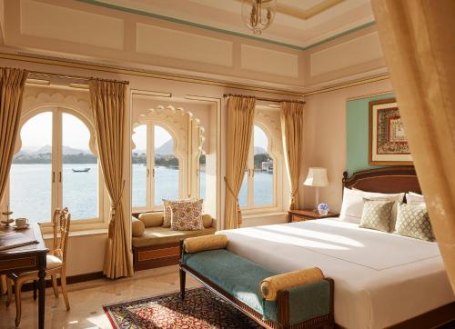 a bedroom with a bed and a desk and windows at Taj Fateh Prakash Palace Udaipur in Udaipur