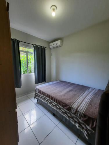 a bedroom with a bed and a window at Casa FLORIANÓPOLIS, Praia de PONTA DAS CANAS,2 in Florianópolis