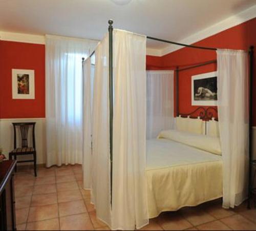 a bedroom with a canopy bed with white curtains at Albergo el Rancho in Bevagna