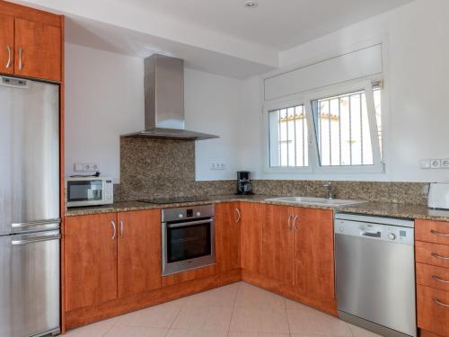 a kitchen with wooden cabinets and stainless steel appliances at Holiday Home Requesens by Interhome in Empuriabrava